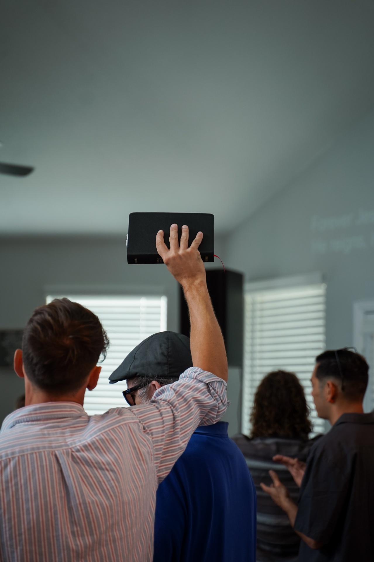 Congregation worshiping with raised Bible during a Sunday gathering